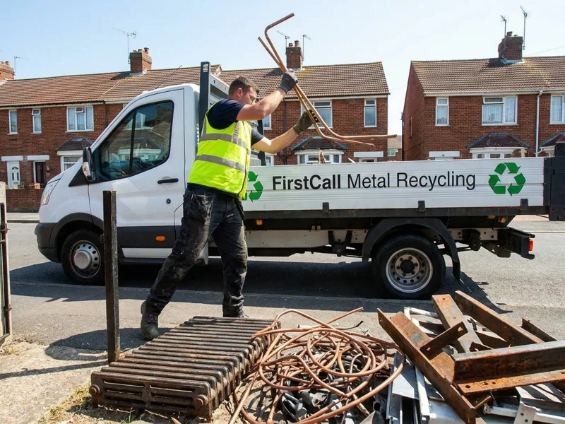 Worker loading scrap metal including radiators and copper pipe into a branded First Call truck on a Southampton residential street